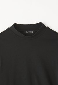 Black high-neck t-shirt made of smooth cotton fabric. Features a minimalistic design with no patterns, labels positioned at the neckline.