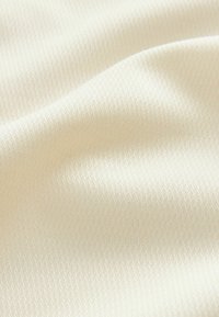 Tissu de couleur crème clair, texturé avec un motif diagonal subtil, texture lisse et tombé doux, adapté à diverses applications textiles.