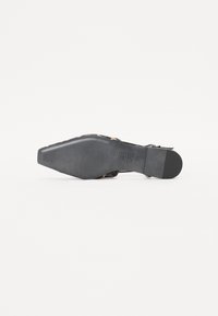 Scarpa nera con tacco alto, punta affilata e suola testurizzata. Presenta un accento a stampa leopardata e un design con cinturino a fibbia.