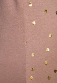 Light pink fabric featuring scattered gold foil polka dots, demonstrating a smooth texture and a simple, playful pattern.