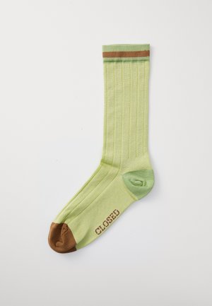 Calcetines verdes con canalé y una puntera marrón, con un acento verde. El nombre de la marca "CLOSED" está bordado en marrón cerca del talón.