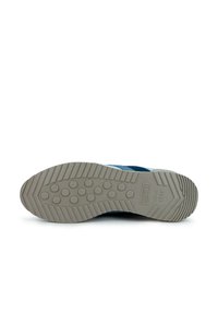 Zapatilla deportiva azul con una suela de goma gris. La suela presenta un patrón circular y ranuras para mayor tracción. Logotipo de la marca en relieve.