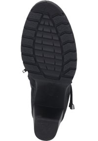 Schwarze Gummisohle mit tiefen Profilen für Traktion, abgerundete Zehen und einem leichtem Absatz mit einer strukturierten Oberfläche für Haltbarkeit.