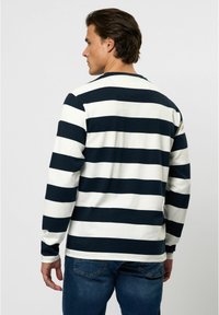 Lange mouwen shirt met marineblauwe en witte horizontale strepen, gemaakt van zachte stof, met een ronde hals en contrasterende stikdetails.