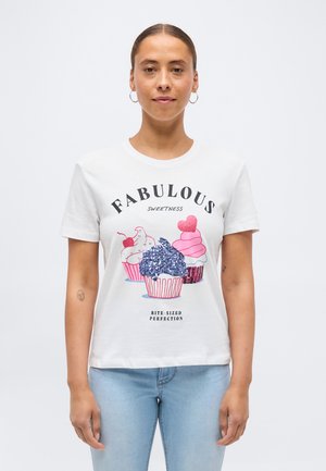Kvinde med øreringe i ringform iført en hvid T-shirt med tre farverige cupcakes og teksten "Fabulous Sweetness Bite-Sized Perfection."