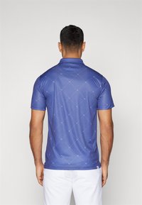 Polo in blu con un motivo a rombi e dettagli bianchi. Realizzato in tessuto liscio con colletto e maniche corte.