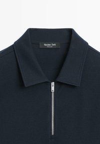 Granatowa koszulka polo wykonana z teksturowanej tkaniny, z przodem zapinanym na zamek i usztywnionym kołnierzem. Etykieta z napisem "Massimo Dutti".