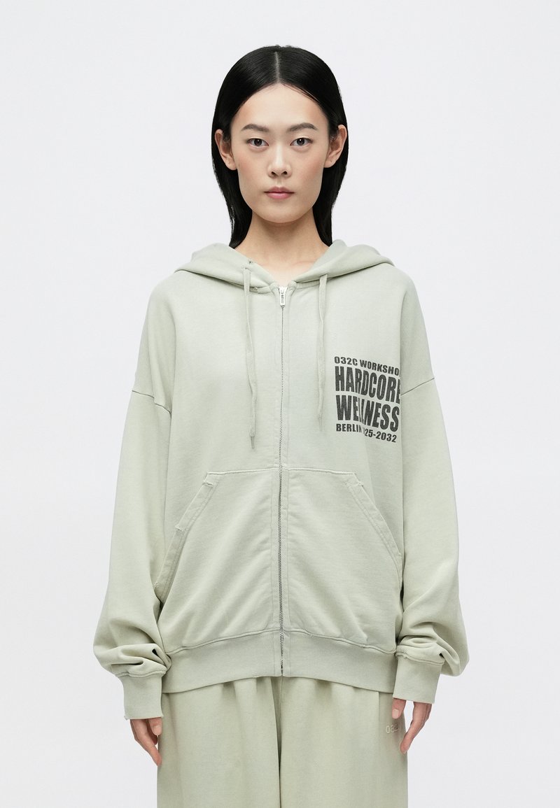 Világoszöld, cipzáras kapucnis pulóver, elöl logónyomattal, laza fazonnal és két elülső zsebbel. Puha anyagból készült, bordázott mandzsettákkal.