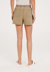 Bermuda khaki con una vita elastica a coste e due tasche posteriori, con una vestibilità ampia e orlo arrotolato, realizzata in tessuto leggero.