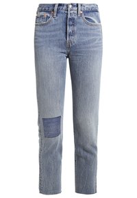 Jean bleu clair taille haute, coupe droite, avec un patch carré bleu foncé sur le genou gauche et un design classique à cinq poches.