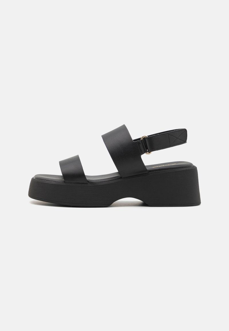 Black platform sandals with two wide straps, a back strap, and a textured sole. Made from synthetic material, featuring a curved silhouette.