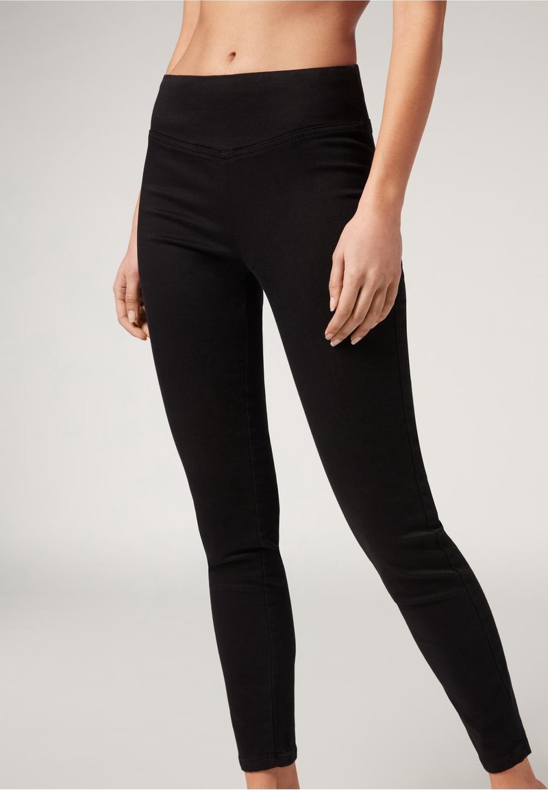 Collants noirs en tissu extensible, avec une taille haute et une coupe ajustée, au toucher lisse et sans motifs visibles.