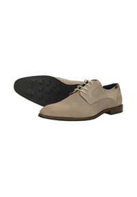 Beige leren jurk schoenen met een gestructureerd oppervlak, ronde neus en platte zwarte rubberen zool met cirkelvormige grippatronen.