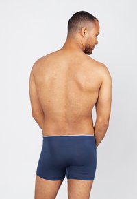 Marineblauwe boxershorts van zacht materiaal met een witte tailleband, met een aansluitend ontwerp en een gladde textuur. Achteraanzicht weergegeven.