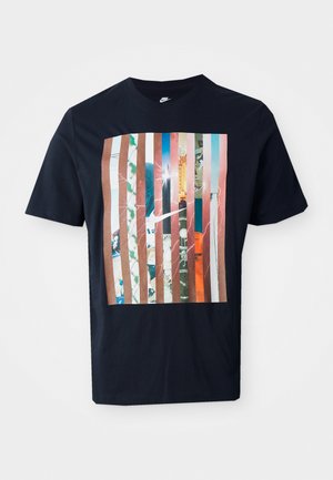 Marineblå t-shirt med et grafisk design med lodrette striber i forskellige nuancer, der inkorporerer urban grafik og et Nike-logo.