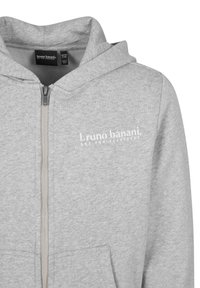 Felpa con zip grigia e texture morbida, con cappuccio regolabile e tasca frontale. Logo stampato sulla parte sinistra del petto.