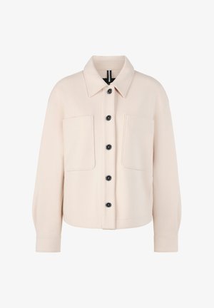 Light beige jacket with a collared neckline, two chest pockets, and black buttons. Fabric appears smooth with a relaxed fit and long sleeves.