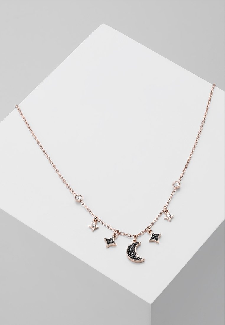 Collier délicat en chaîne en or rose avec des pendentifs en pierres précieuses noires et blanches en forme de croissant de lune et de cinq étoiles, présenté sur une surface blanche.