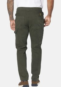 Olive green cargo pants with a relaxed fit, elastic waistband, multiple spacious side and back pockets, and a textured fabric finish.