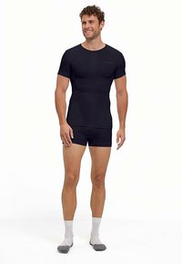 Maglietta atletica aderente nera e pantaloncini realizzati in materiale elasticizzato, con maniche corte e design senza cuciture per il massimo comfort.