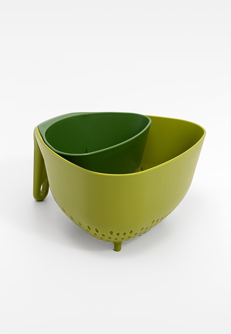 Colador de plástico verde con dos compartimentos, que cuenta con un exterior liso, base perforada y un mango resistente para un drenaje fácil.