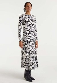 Vestido de manga larga en un patr�ón floral en blanco y negro, con corsé ajustado y falda acampanada, combinado con botas negras hasta el tobillo.