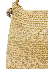 Szőtt sárga táska, amely bonyolult textúrájú mintákkal és színes díszítéssel ellátott fonott füllel készült. Természetes anyagokból készült.
