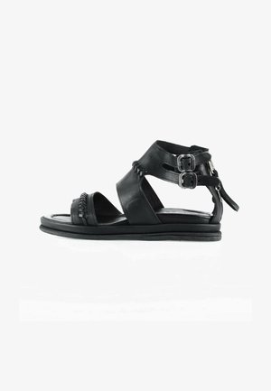 Sandale plate en cuir noir avec détail tressé, deux brides réglables à la cheville avec boucles argentées et une fermeture éclair à l'arrière.