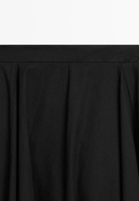 Gonna nera con design plissettato, realizzata in tessuto liscio. Presenta una cintura larga e una silhouette fluida. Design minimalista e versatile.