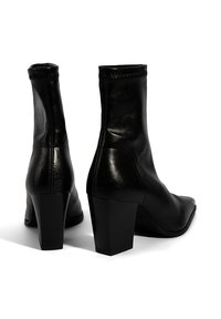 Bottines en cuir noir avec un bout carré, texture lisse et un talon épais. Présente une couture latérale et un design de cheville cousu.
