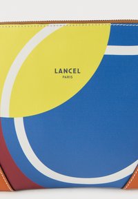Έγχρωμο νεσεσέρ Lancel Paris με γεωμετρικά μοτίβα σε κίτρινο, μπλε και κόκκινο, με λευκό καμπυλωτό στοιχείο, κατασκευασμένο από υλικό με υφή.