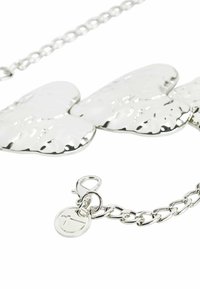 Srebrny naszyjnik z dużymi, teksturowanymi, w kształcie serca zawieszkami oraz łańcuszkiem z zapięciem typu karabińczyk i metką z logo.