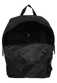 Sac à dos noir avec un grand compartiment principal, fermeture éclair, poches intérieures et une poche latérale en maille. Présente un design de logo subtil.