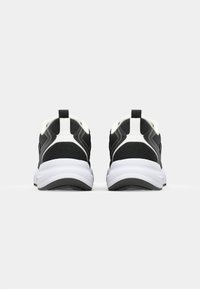 Μαύρα αθλητικά παπούτσια με επάνω μέρος από διχτυωτό ύφασμα και λευκές λεπτομέρειες. Διαθέτουν επενδεδυμένο κολάρο, υφασμάτινη σόλα και ταμπελάκι στο πίσω μέρος.