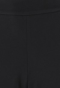 Tessuto nero con una texture diagonale, caratterizzato da una finitura liscia e una cucitura pulita in vita e lungo il lato.