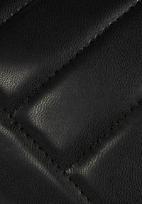 Materiale in pelle nera con una superficie texturizzata. Presenta sezioni imbottite con cuciture visibili e una leggera lucentezza.