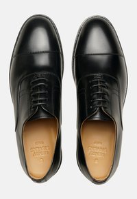 Schwarze Leder-Dressschuhe mit glatter Oberfläche, runder Zehenform und strukturiertem Schnürsystem. Ausgestattet mit braunen Einlegesohlen und dezenten Nähdetails.