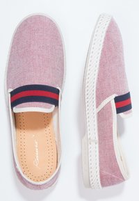 Scarpe slip-on in tessuto rosso e bianco con una fascia elastica a righe blu e rosse, suola in gomma bianca e soletta imbottita color nocciola.