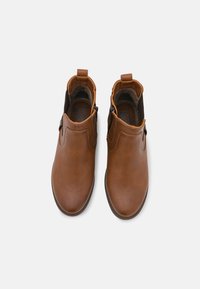 Bottes de cheville en cuir marron avec une texture lisse, des panneaux latéraux élastiques et une petite languette au talon, dotées d'un design à bout rond.