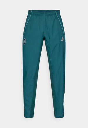 Pantalones deportivos en color verde azulado con una textura sutil, cintura elástica, bolsillos con cremallera y rayas en contraste. Incluyen el logo de Adidas y el escudo del Arsenal.