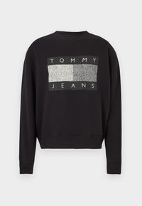 Sudadera negra con cuello redondo, puños y dobladillo acanalados, con un rectángulo texturizado en gris y blanco y el texto "TOMMY JEANS" en el pecho.