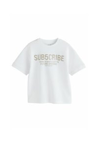 Vit t-shirt med kort ärm gjord av bomull. Har fettryckt text i ljusbeige. Rund halsringning och avkopplad passform.