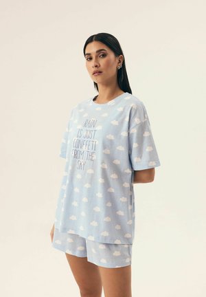 Jasnoniebieskie bawełniane ubrania do wypoczynku z wzorem chmur. T-shirt ma centralny nadruk, luźny krój, krótkie rękawy oraz pasujące szorty.