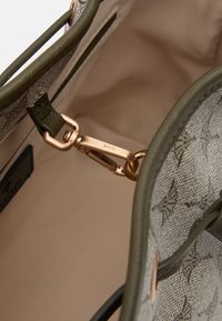 Interior de bolsa de couro verde com forro em tecido bege, apresentando um fecho de metal dourado e um padrão embutido subtil no tecido.