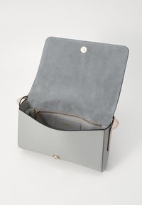 Borsa a mano in pelle grigia con una texture morbida, dotata di chiusura a scatto magnetico, tasca con zip interna e un design minimalista. L'interno è foderato in suede.