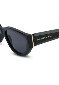 Černé sluneční brýle s lesklým povrchem, velké čočky, zlaté akcenty na stranách a logo na jedné straně.