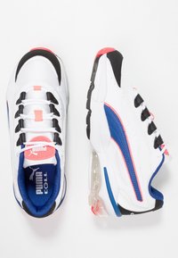 Baskets blanches Puma Cell avec des accents bleu, noir et corail, semelle amortissante visible et tissu en mesh, vues de dessus et de côté.