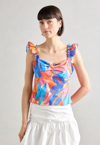Haut court coloré avec des motifs de feuilles bleues, orange et roses ; présente des bretelles volantes et une coupe ajustée. Le tissu texturé apporte un intérêt visuel.