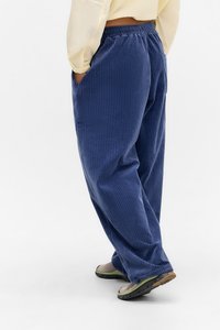 Marineblauwe corduroy broek met een losse pasvorm, elastische tailleband en zijzakken. De stof heeft een verticale geribbelde structuur.