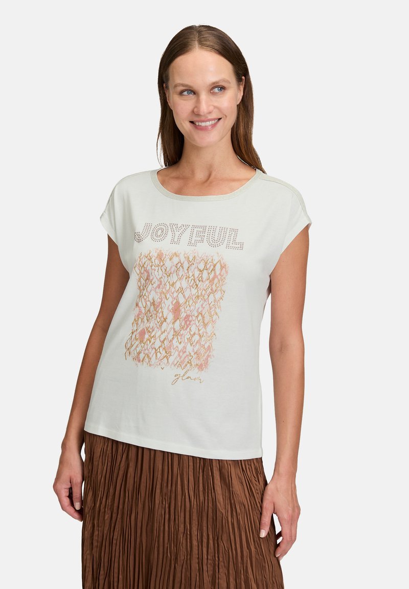 Jasnozielona koszulka z krótkim rękawem z tekstowym wzorem "RADOSNY" z błyszczącymi akcentami, z wzorzystym kwadratem w odcieniach różu i brzoskwini.